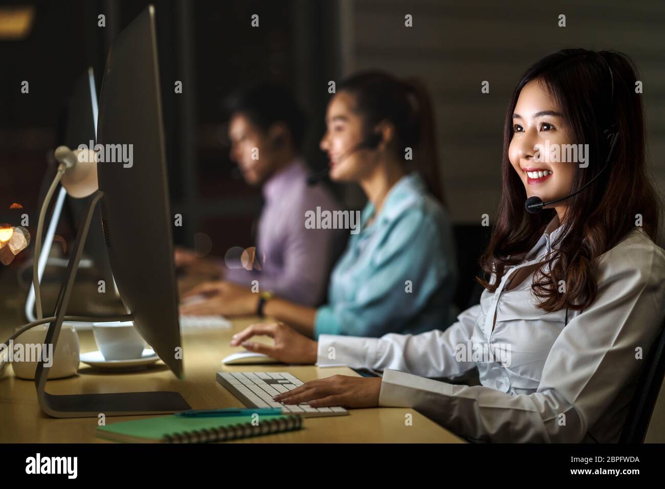 Asian Femme service client avec homme d'affaires souriant et travaillant dur tard dans le quart de nuit au bureau, service de centre d'appels, travailleur et heures supplémentaires Banque D'Images
