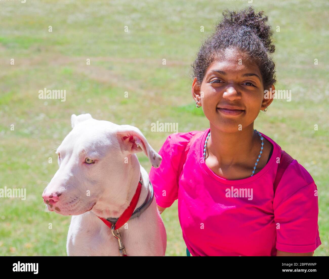 Jeune entraîneur brésilien de chien avec beau chien blanc avec de grands yeux jaunes Banque D'Images Jeune entraîneur brésilien de chien avec beau chien blanc avec de grands yeux jaunes Banque D'Images