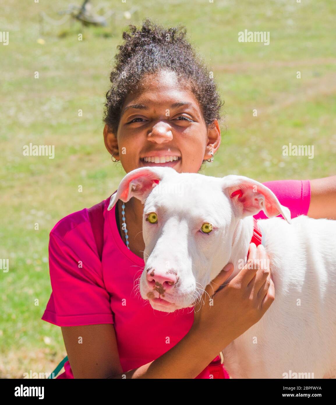 Jeune entraîneur brésilien de chien avec beau chien blanc avec de grands yeux jaunes Banque D'Images Jeune entraîneur brésilien de chien avec beau chien blanc avec de grands yeux jaunes Banque D'Images