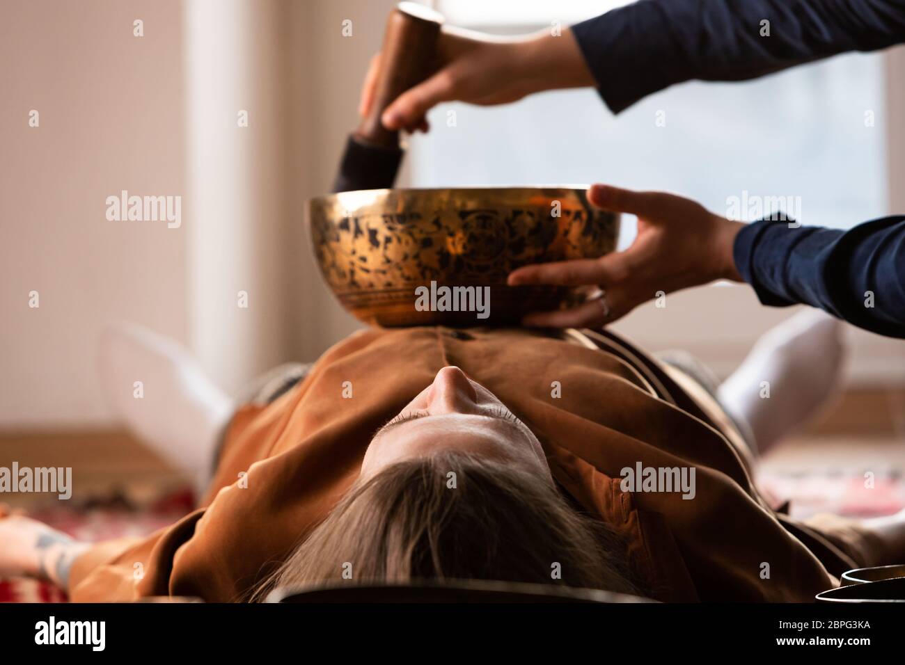 Femme faisant massage relaxant, méditation, thérapie sonore avec des bols de chant tibétien. Soulagement de stress. Mise au point sélective. Vue de dessous. Banque D'Images