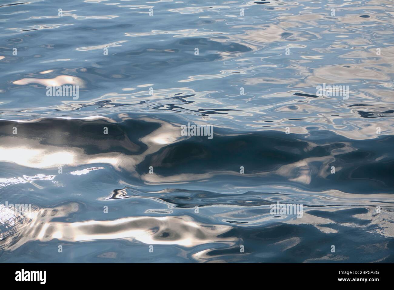 Motifs abstraits et réflexions de lumière à la surface de la mer avec de petites ondelettes Banque D'Images