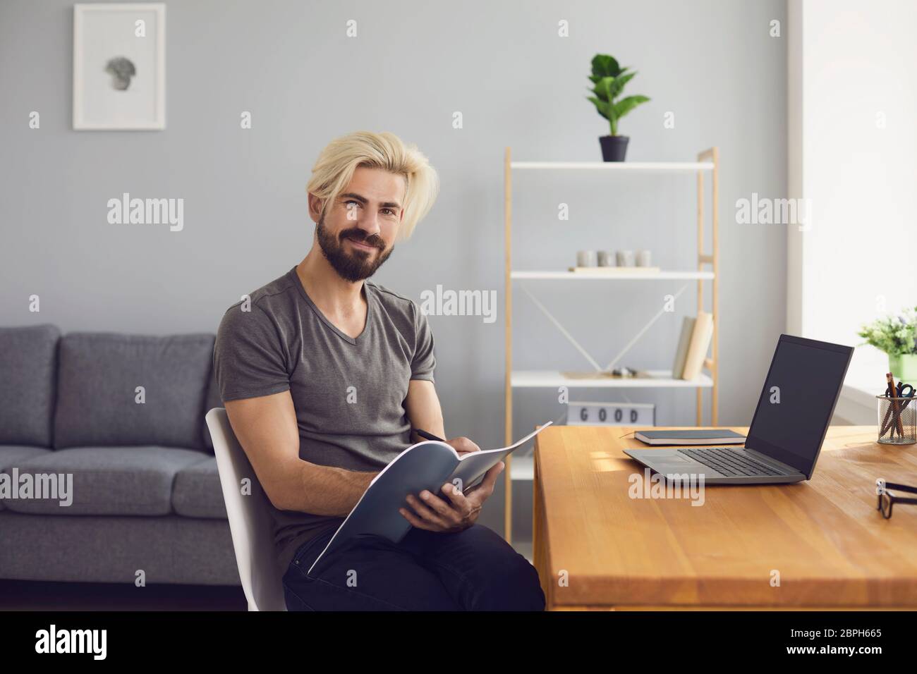 Formation en ligne. Happy Guy prépare un projet pour une leçon en utilisant un cours d'appel vidéo portable assis à une table à la maison. Banque D'Images