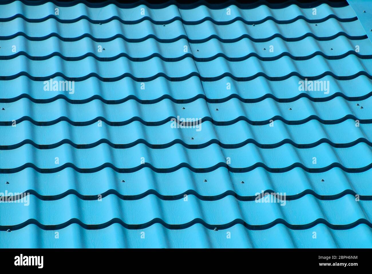 Carreaux de métal turquoise sur le toit de la maison. Matériaux de toiture modernes Banque D'Images