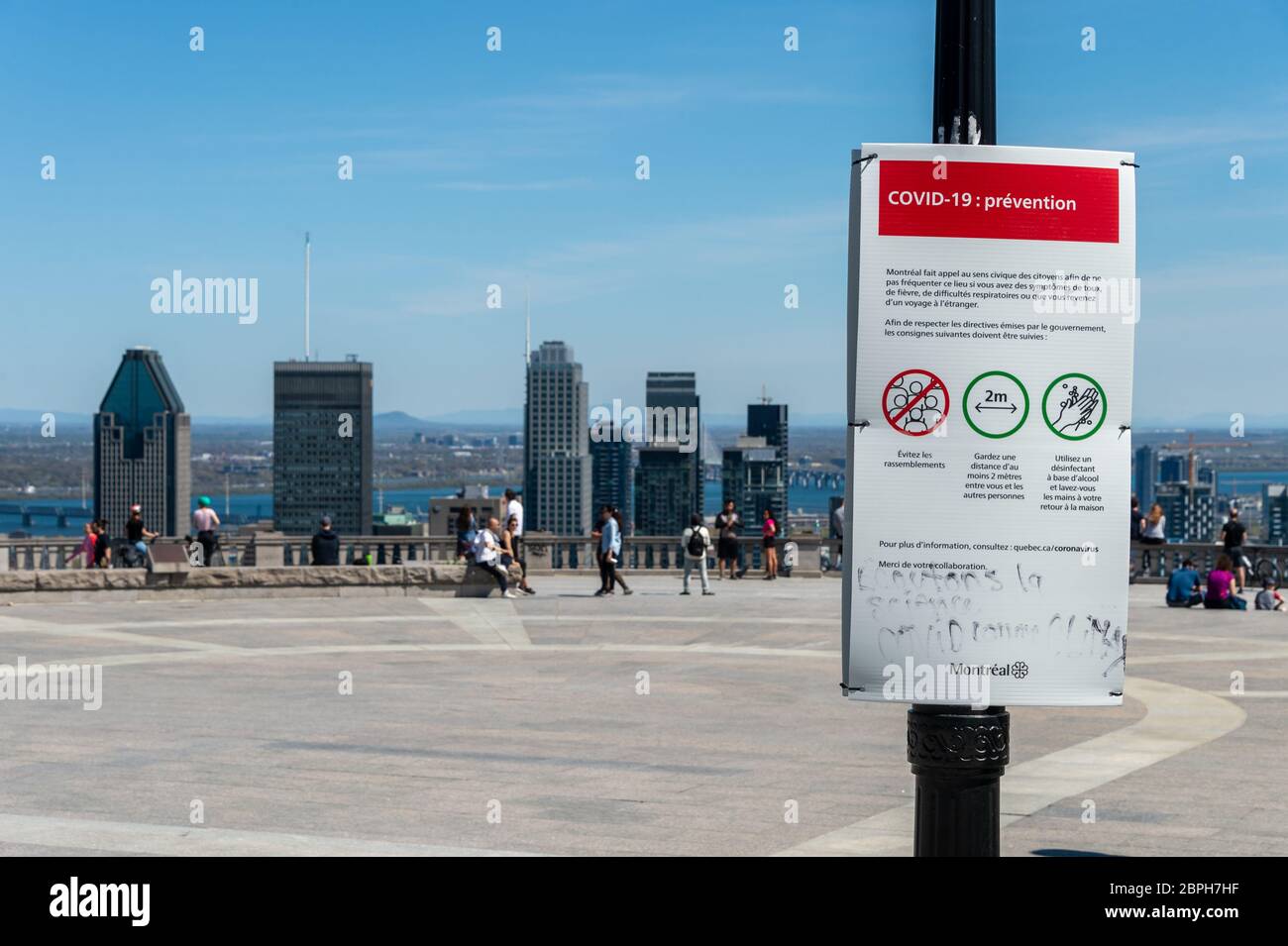 Montréal, CA - 18 mai 2020 : affiche montrant les lignes directrices françaises Covid-19 et les gratte-ciel de Montréal au loin. Banque D'Images