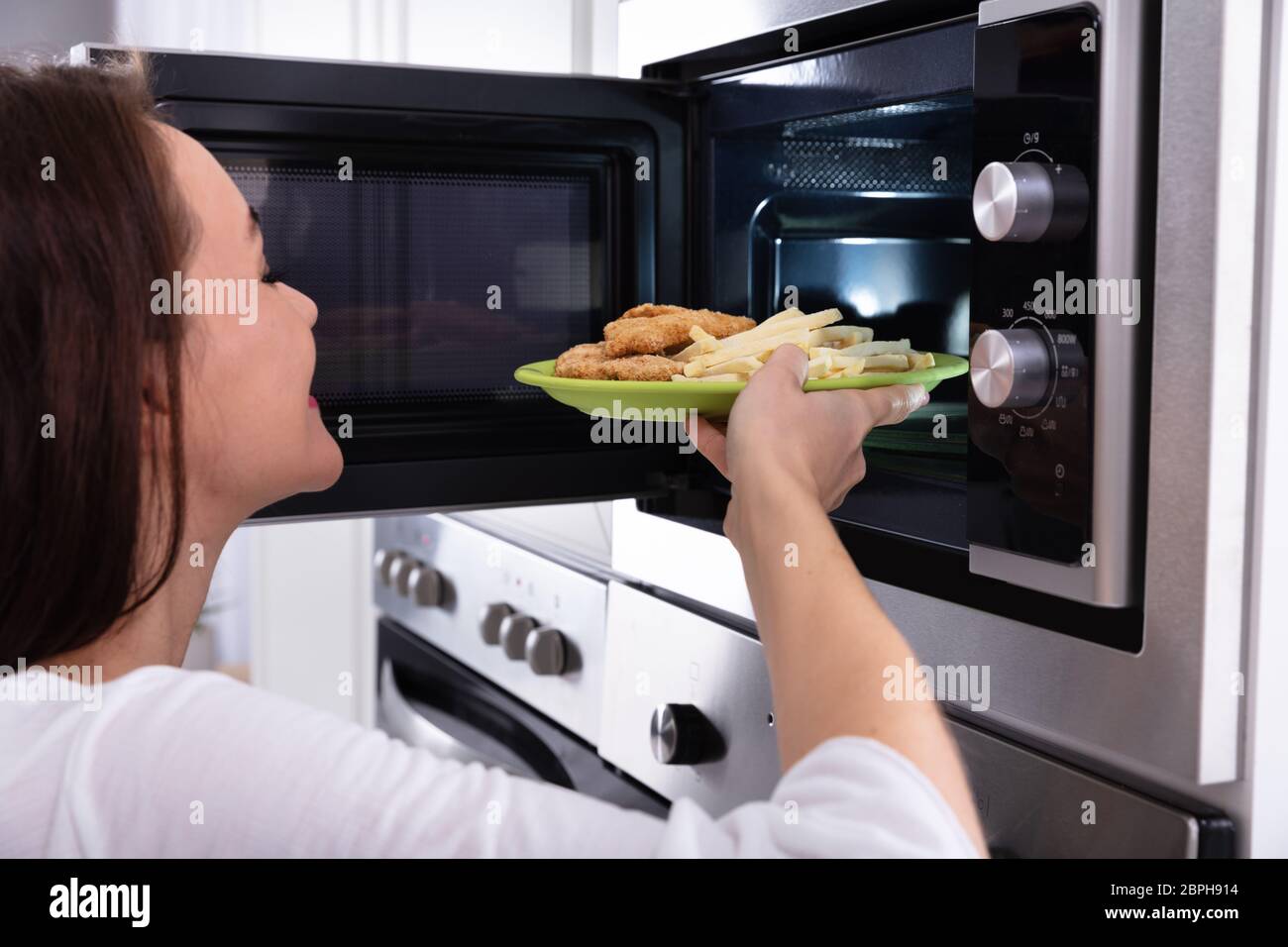 Close-up of a Young Woman Chauffage Les aliments frits dans un four micro-ondes four Banque D'Images