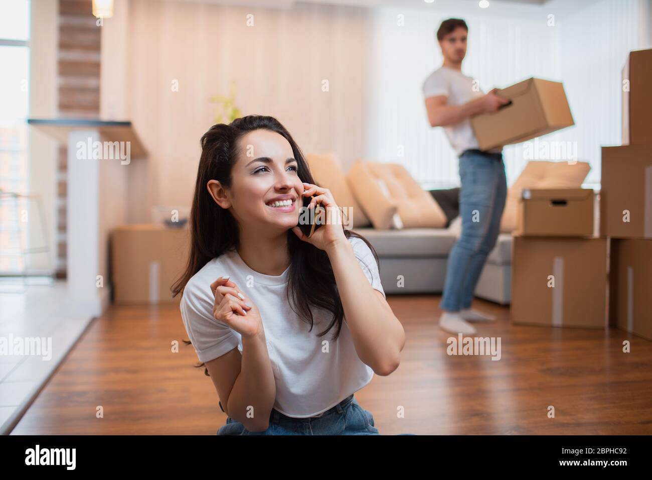 Le mari porte des boîtes, et la femme parle au téléphone. Banque D'Images