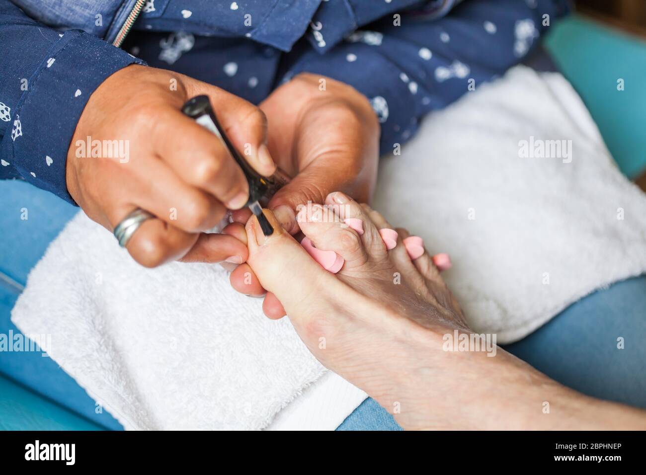 Gros plan d'un pied de femme senior tout en obtenant une pédicure à la maison pendant la pandémie Covid-19 Banque D'Images