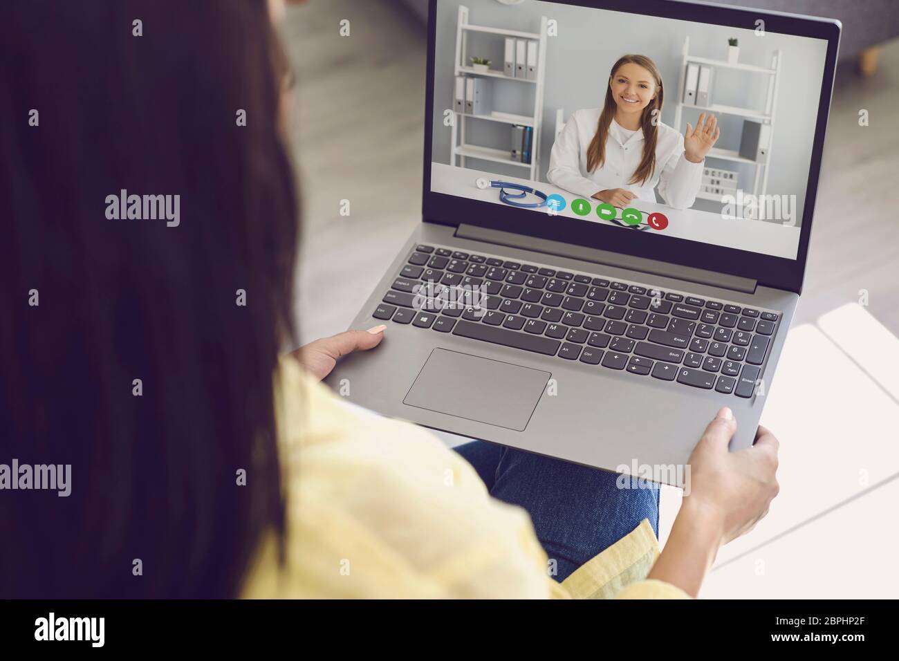 Médecin en ligne. Une femme vêtue de vêtements décontractés écoute un appel vidéo en consultant un médecin depuis un ordinateur portable skype à la maison. Banque D'Images
