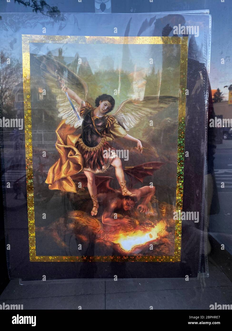 Photo de Saint Michael, le protecteur de Satan accroché sur une porte en verre avec des réflexions de la rue, Brooklyn, New York. Banque D'Images