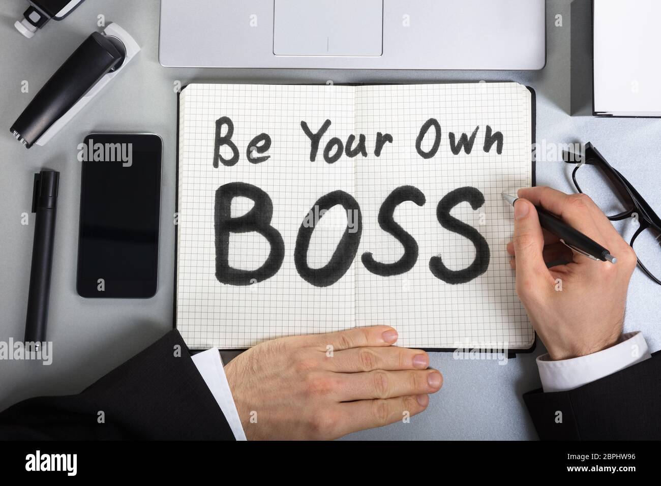 Portrait Of A Businessman's Hand Writing Soyez votre propre patron Texte sur ordinateur portable Banque D'Images