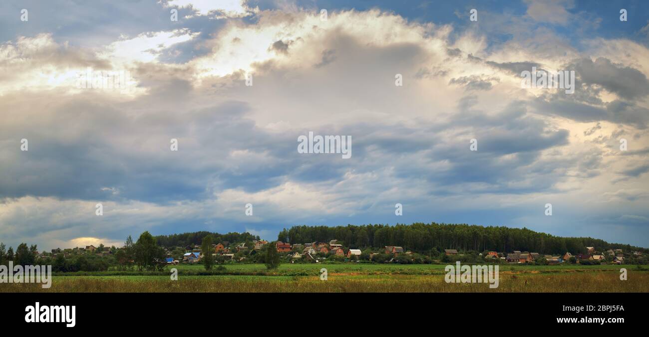 Paysage rural pittoresque. Scenic ciel avec les nuages, les maisons et les arbres. Vue panoramique tourné. Banque D'Images
