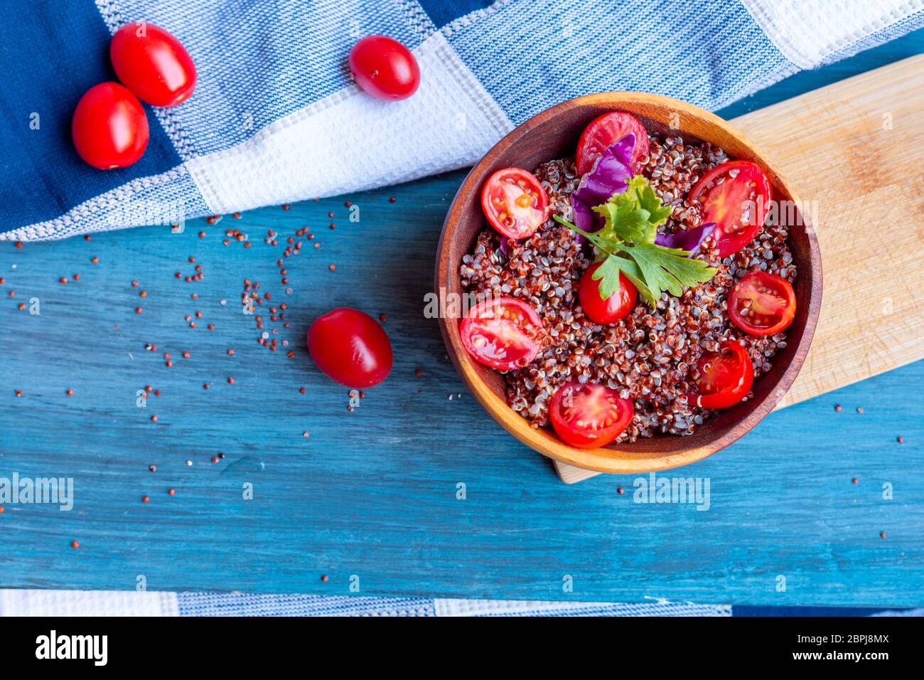 Salade de quinoa rouge avec tomate sur une table rustique. Concept de superalimentation et de saine alimentation. Banque D'Images