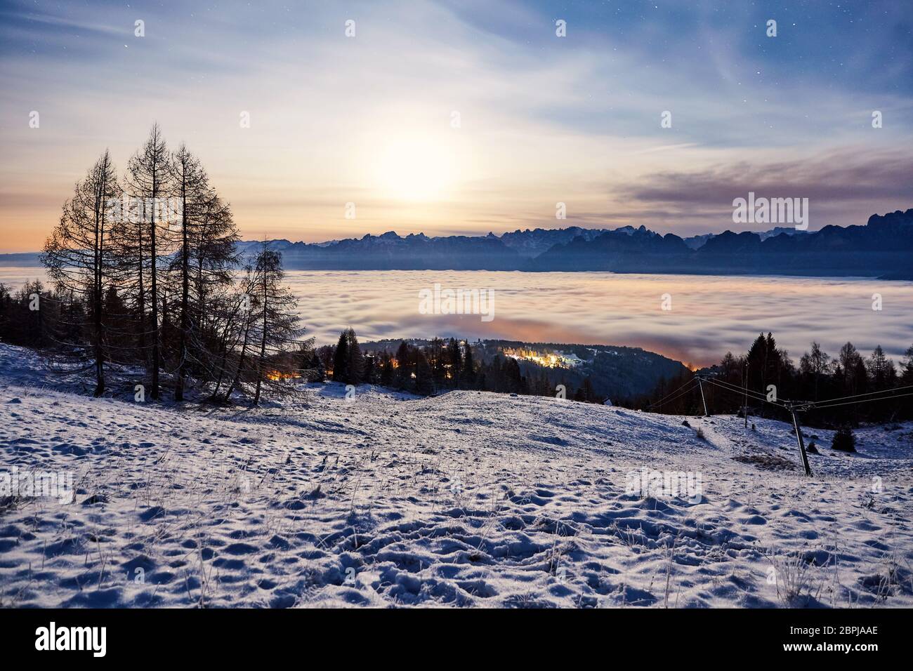 Montagnes de dolomie couvertes de neige au coucher du soleil. Exposition longue. Tapis de nuage sur fond. Belluno, Italie Banque D'Images