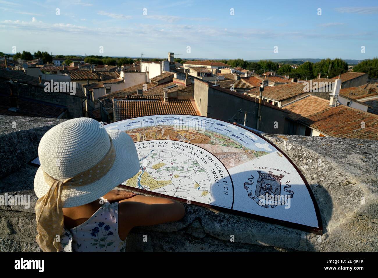 Une jeune fille avec chapeau devant la carte d'orientation sur un mur en pierre surplombe la ville d'Arles.Bouches-du-rhône.Alpes-Côte d'Azur.France Banque D'Images