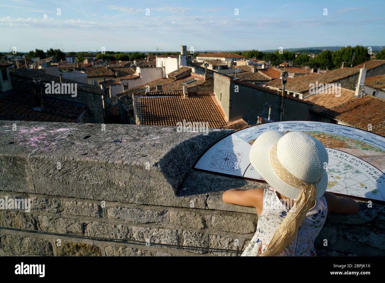 Une jeune fille avec chapeau devant la carte d'orientation sur un mur en pierre surplombe la ville d'Arles.Bouches-du-rhône.Alpes-Côte d'Azur.France Banque D'Images