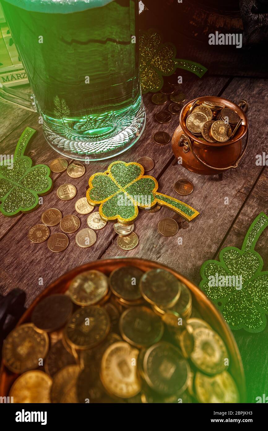 Les trèfles trèfles vert sur fond de bois avec beaucoup de pièces d'or et d'un pichet de bière Banque D'Images