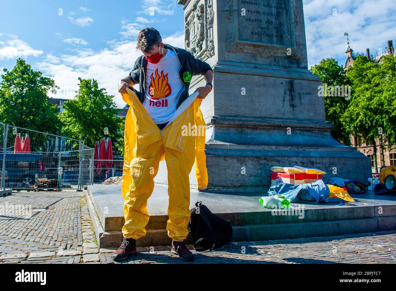 Un militant climatique est vu mettre un costume de protection jaune avec un t-shirt contre Shell. Lors de l'assemblée annuelle des actionnaires de Shell, le Code des groupes climatiques Rood, Shell doit tomber et Greenpeace a organisé une manifestation contre la compagnie pétrolière, devant le siège social de Shell. Les groupes climatiques ont protesté contre l'entreprise et ont exigé que l'entreprise soit démantelée. Le groupe climat, la rébellion de l'extinction, a également montré son soutien aux manifestations en menant une représentation avec les rebelles noirs devant la Chambre des représentants à la Haye. Les manifestations ont été entourées Banque D'Images