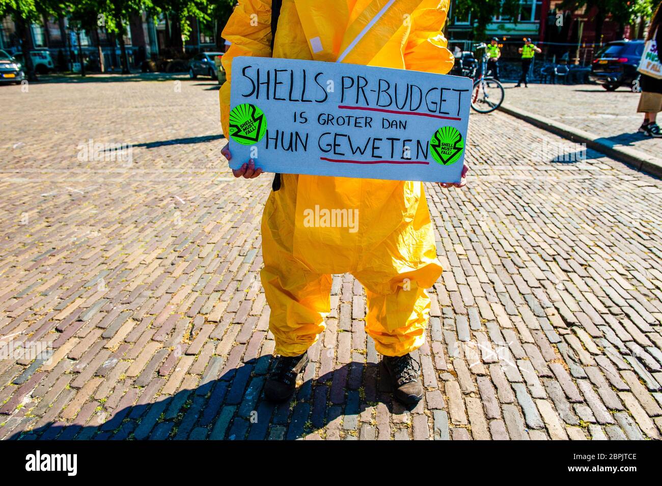 Un militant climatique est vu porter une combinaison de protection jaune tout en tenant une pancarte. Lors de l'assemblée annuelle des actionnaires de Shell, le Code des groupes climatiques Rood, Shell doit tomber et Greenpeace a organisé une manifestation contre la compagnie pétrolière, devant le siège social de Shell. Les groupes climatiques ont protesté contre l'entreprise et ont exigé que l'entreprise soit démantelée. Le groupe climat, la rébellion de l'extinction, a également montré son soutien aux manifestations en menant une représentation avec les rebelles noirs devant la Chambre des représentants à la Haye. Les manifestations ont été entourées d'un concert Banque D'Images