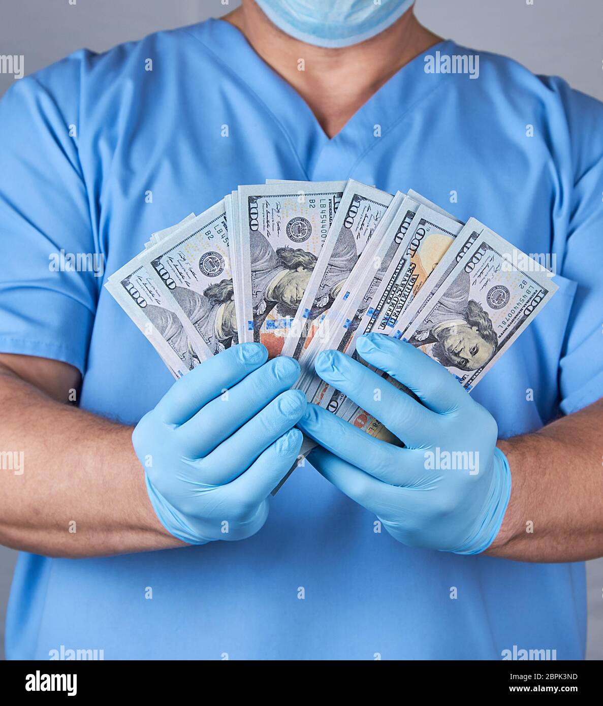 Médecin en uniforme bleu et des gants stériles en latex est titulaire d'un lot de papier-monnaie, le concept de la corruption en médecine Banque D'Images