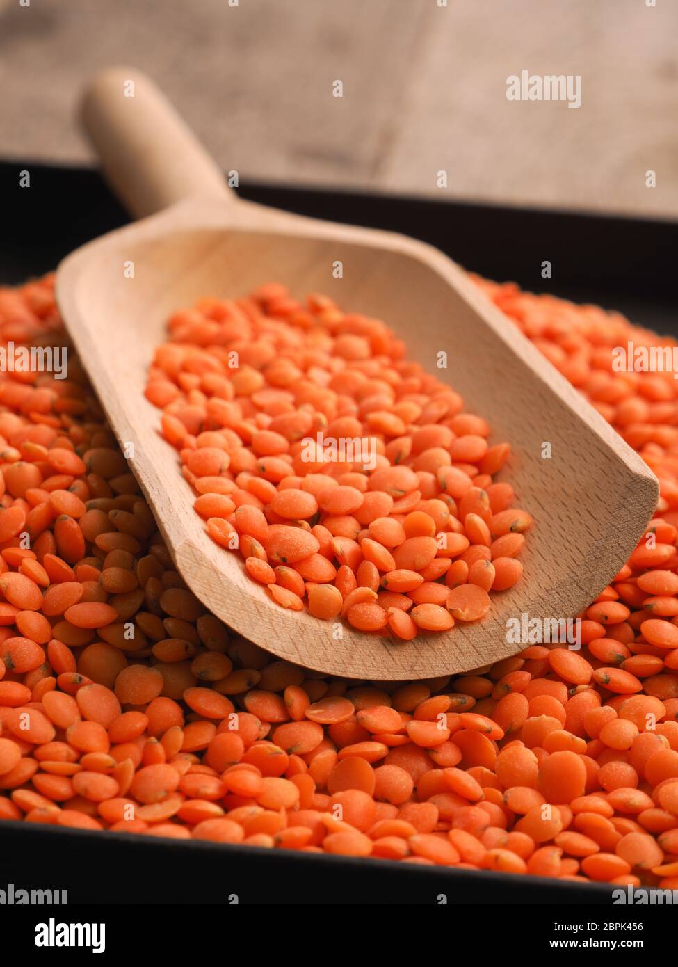 Les lentilles rouges bio avec une pelle en bois sur une table de cuisine Banque D'Images