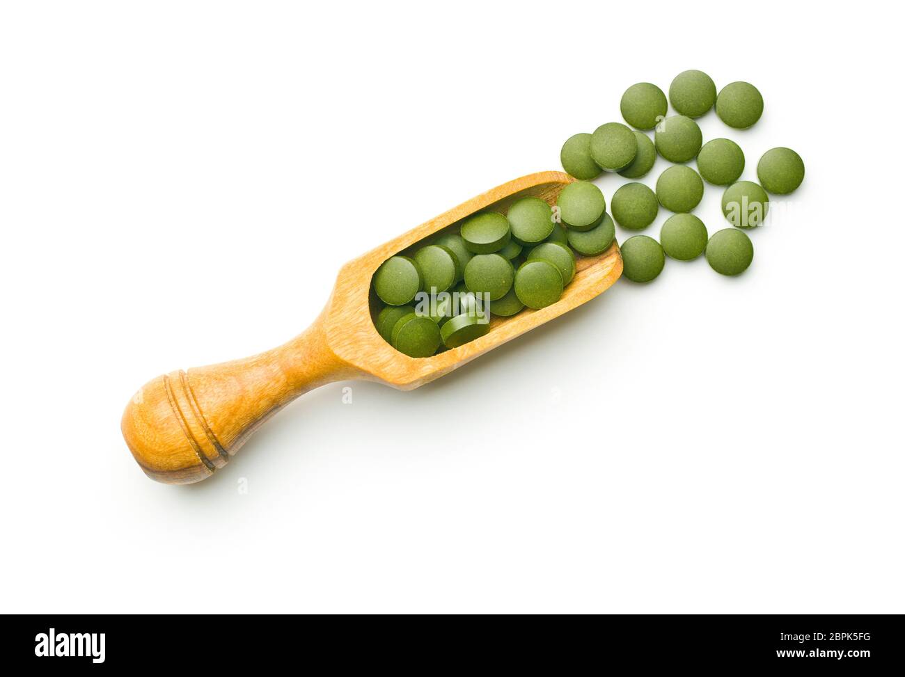 La chlorelle vert comprimés ou l'orge en pillsin scoop en bois isolé sur fond blanc. Banque D'Images