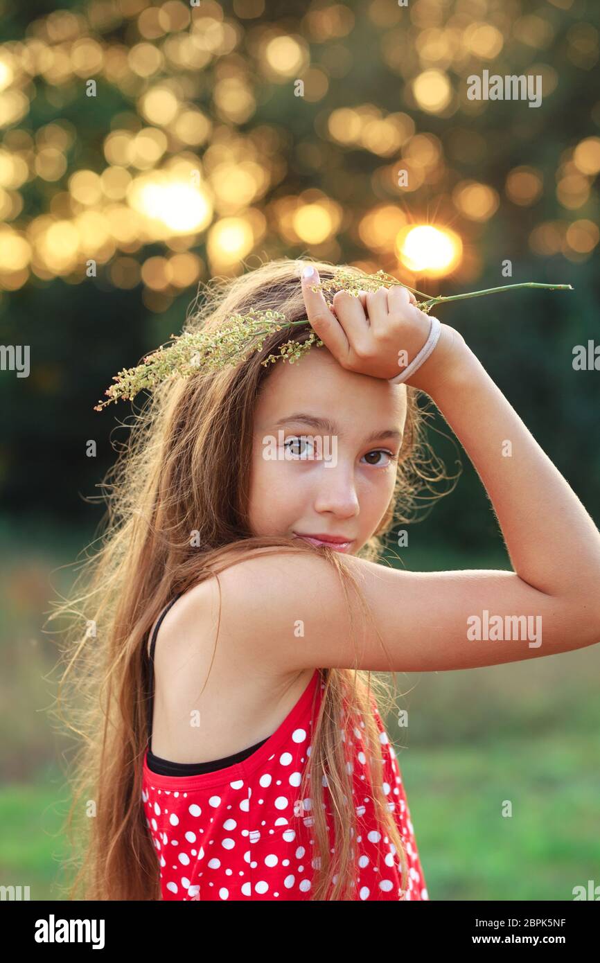 Belle Teen Girl est souriante et aime la nature dans le parc au coucher du soleil d'été Banque D'Images