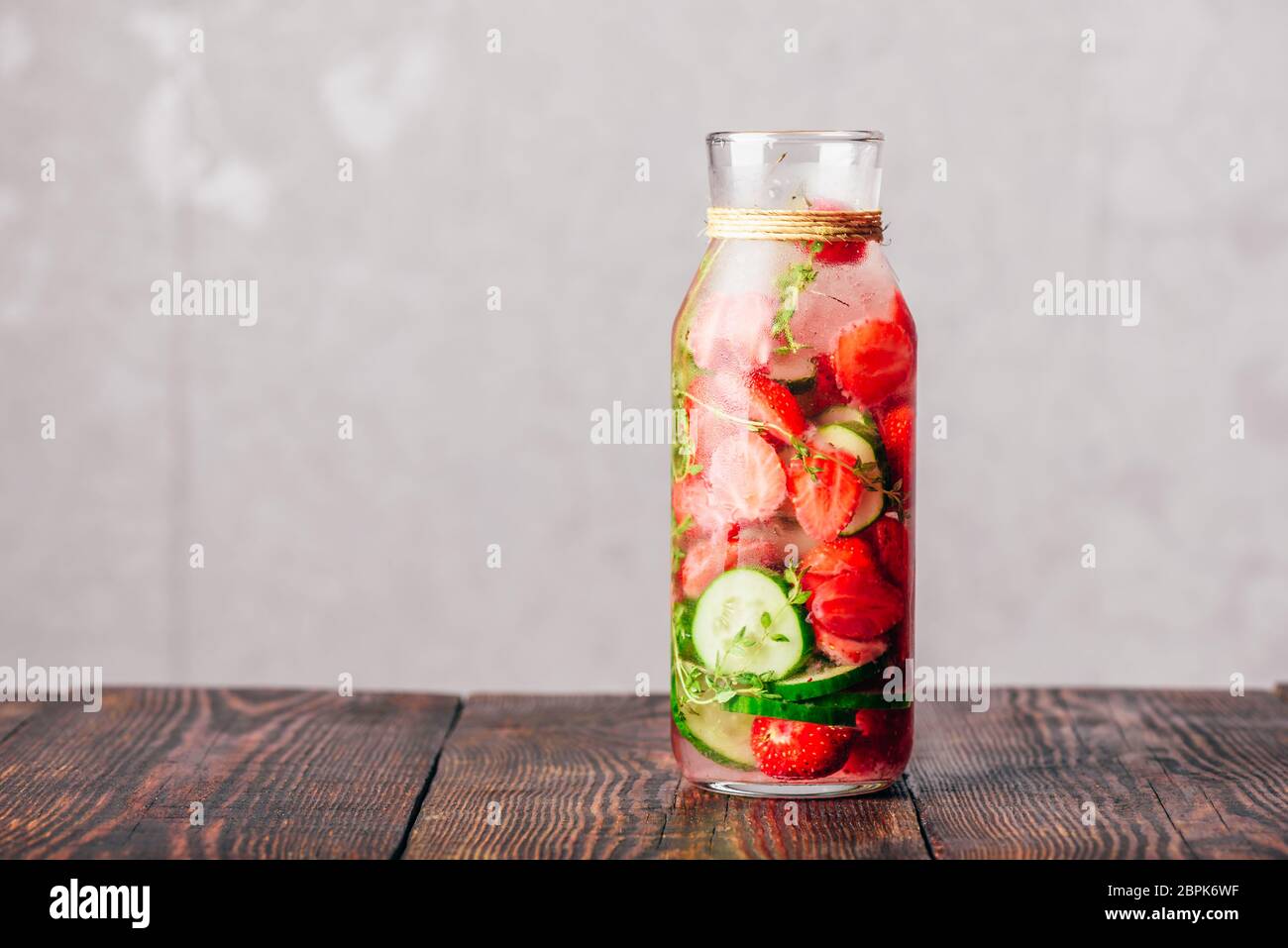 Bouteille de l'eau avec des fraises fraîches de Detox, tranches de concombre et les ressorts de thym. Copier l'espace. Banque D'Images