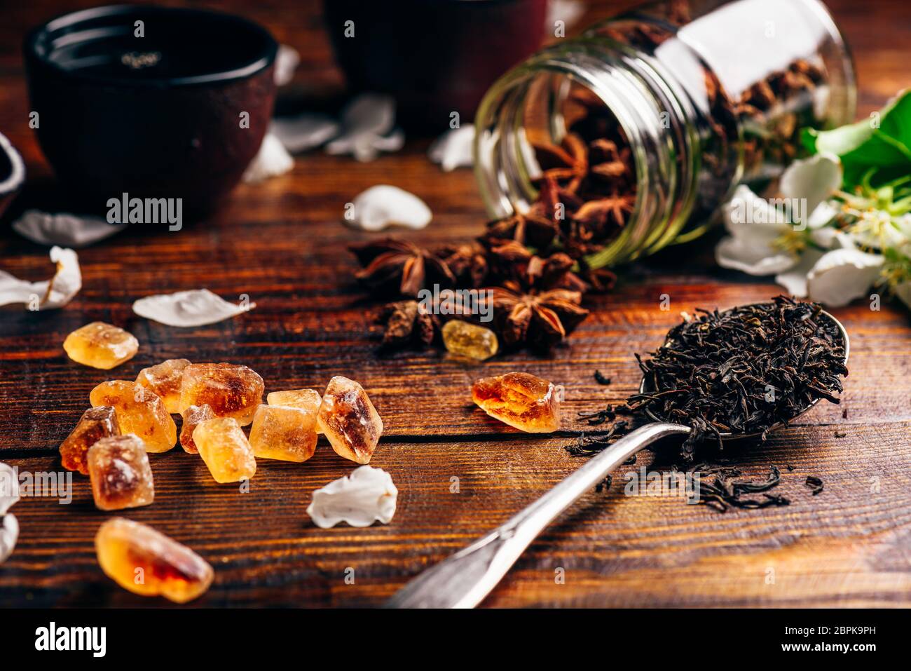 Cuillerée de thé, de sucre et d'Apple Fleurs, étoile d'anis éparpillés sur la table en bois. Banque D'Images
