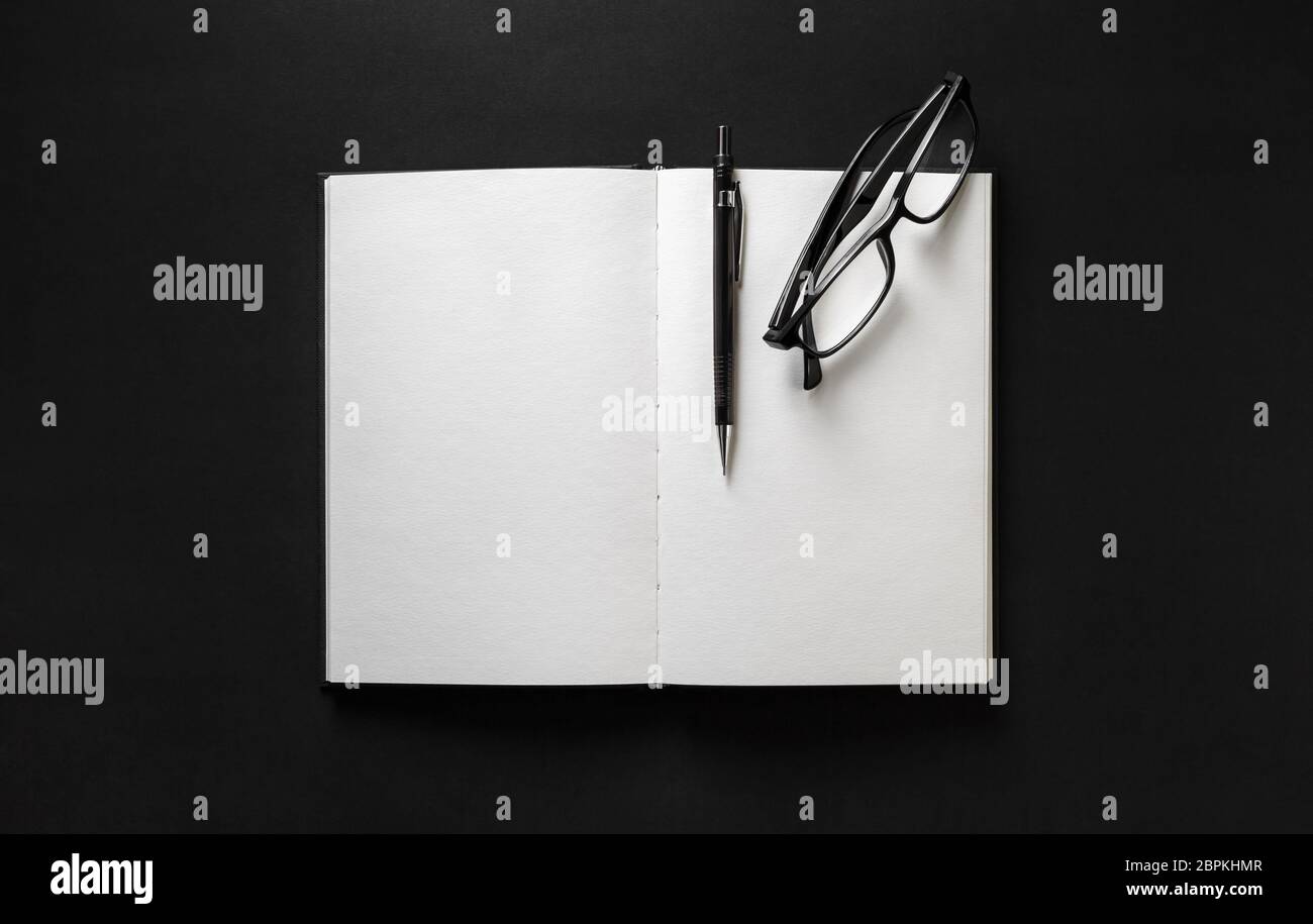 Livre blanc ouvert, verres et un stylo noir sur fond de papier. Mise à plat. Banque D'Images