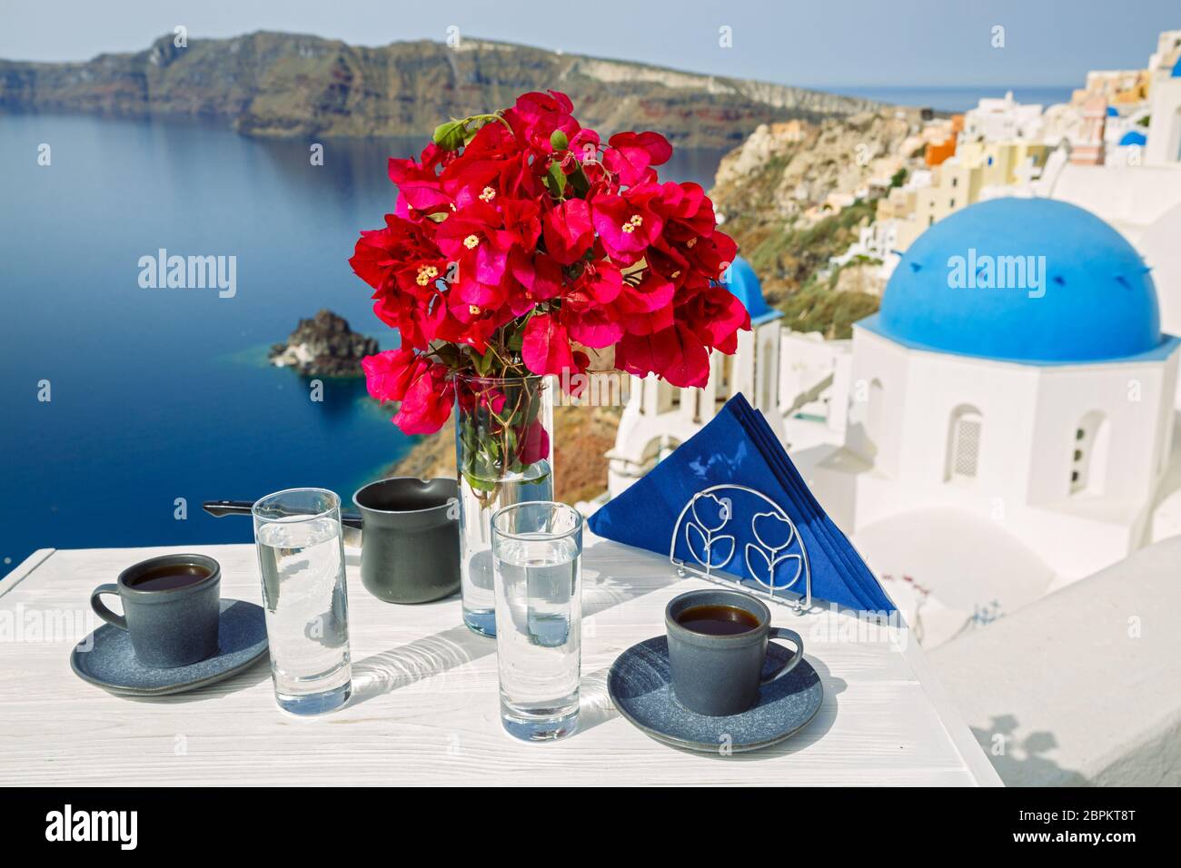 Boissons et fleurs sur la table avec vue sur le paysage de l'île de Santorin Banque D'Images