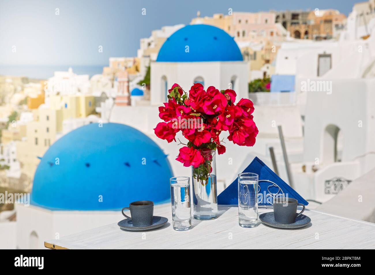 Boissons et fleurs sur la table avec vue sur le paysage de l'île de Santorin Banque D'Images
