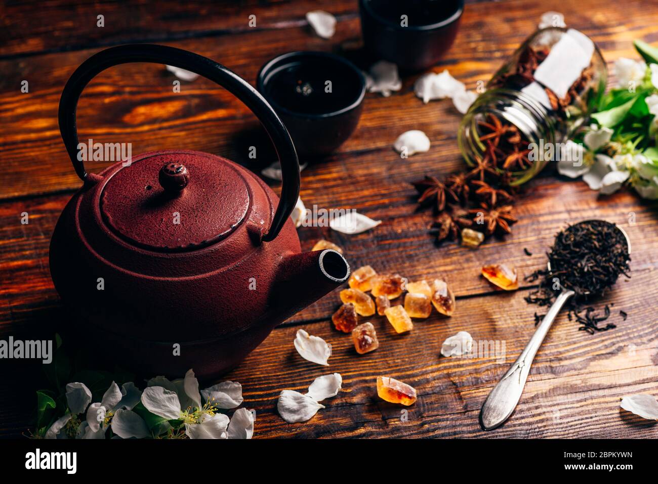 Théière avec cuillère de thé, de sucre et d'Apple Fleurs, étoile d'anis sur table en bois. Banque D'Images