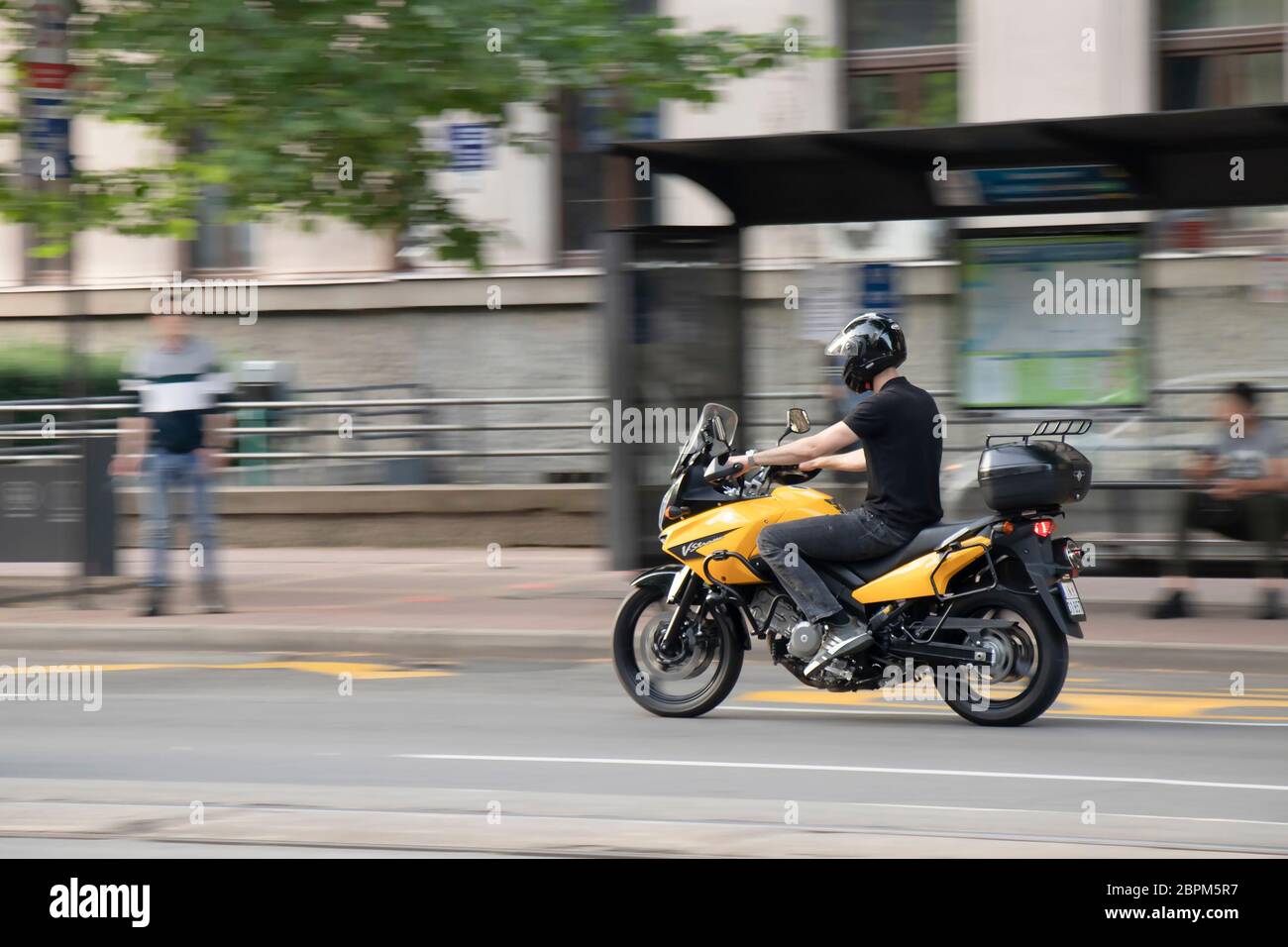 Belgrade, Serbie - 14 mai 2020 : jeune homme à vélo jaune dans la rue de la ville, en panoramique et en mouvement flou Banque D'Images