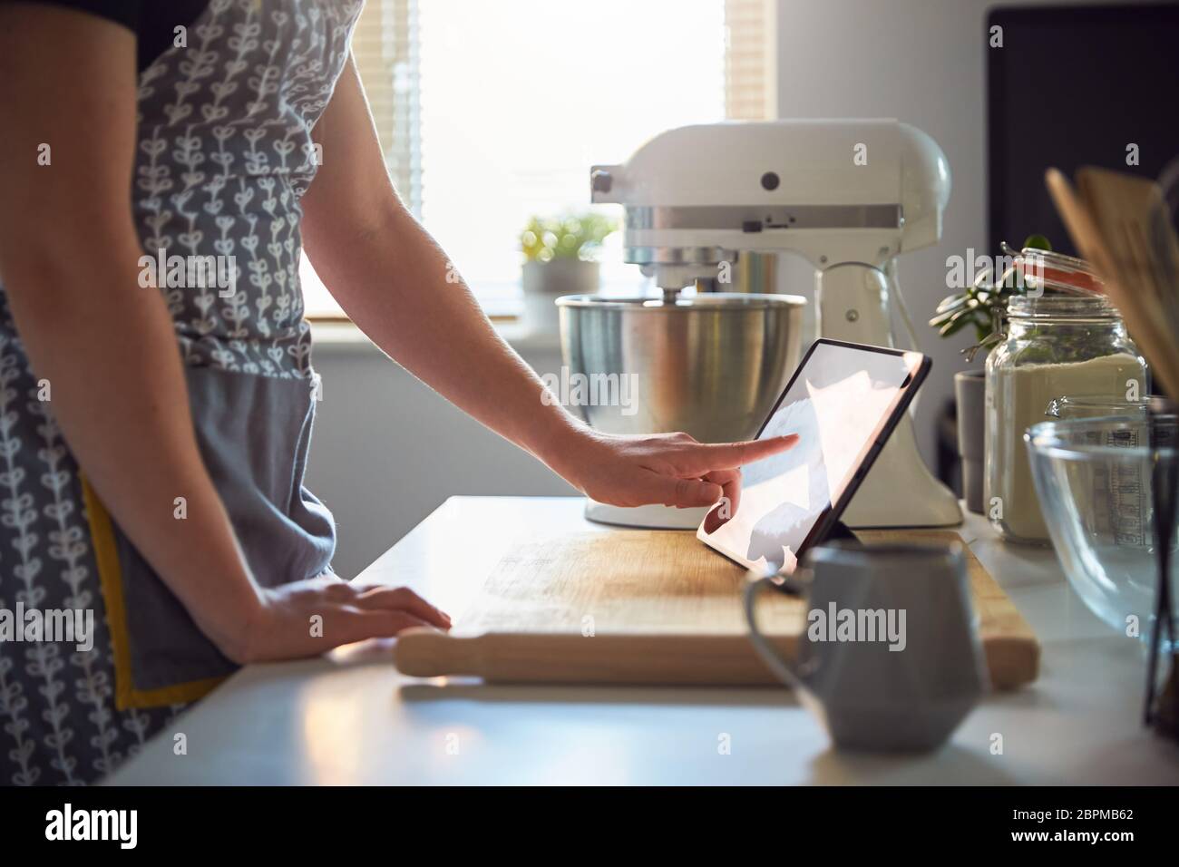 Femme utilisant un écran tactile sur une tablette numérique dans la cuisine à la maison sur une planche à découper Banque D'Images