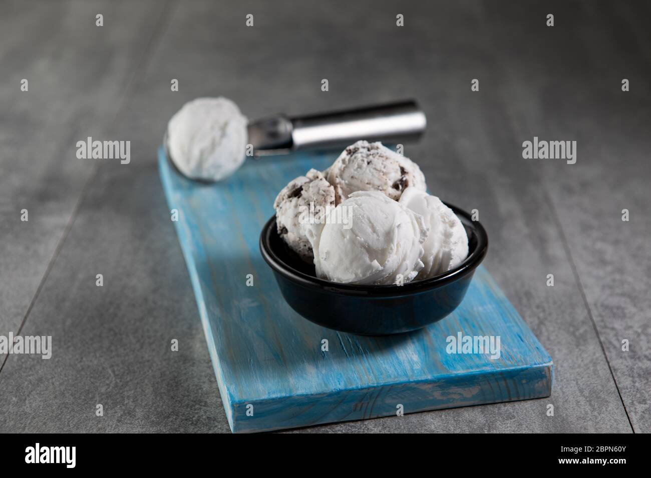 Crème glacée aux produits laitiers et à la stracciatella dans un bol à dessert noir Banque D'Images