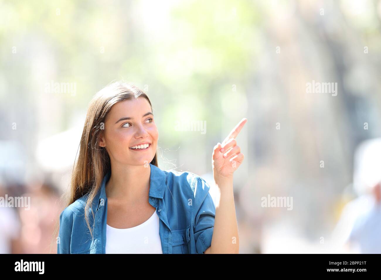 Frint voir portrait of a happy girl pointing at côte dans la rue un jour ensoleillé Banque D'Images