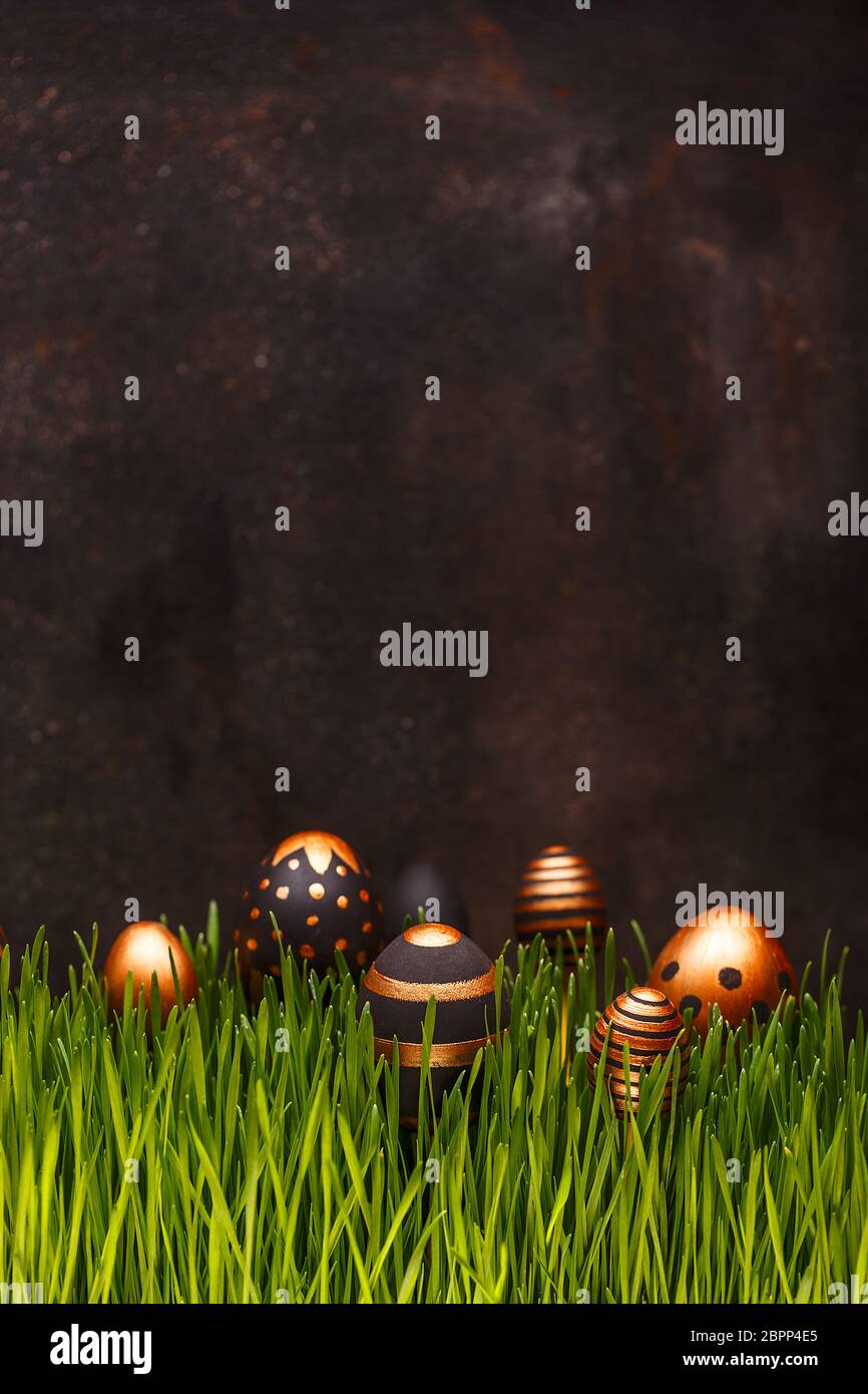 Composition de Pâques avec œufs dorés et noirs se cachant dans l'herbe verte, espace copie Banque D'Images