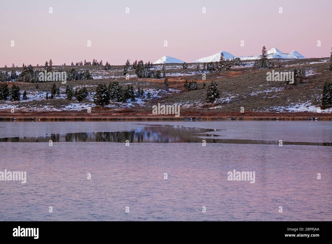 WY04441-00...WYOMING - Dawn au lac Swan partiellement gelé avec la neige couverte de Gallantin Range au-delà dans le parc national de Yellowstone. Banque D'Images
