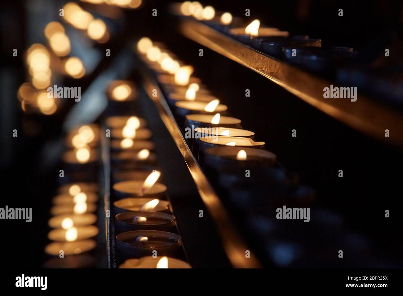 Rangées de bougies allumées dans une église dim Banque D'Images