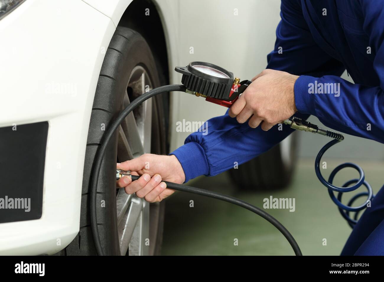 Close up d'un mécanicien de voiture mains contrôle de l'air des pneus avec un manomètre Banque D'Images