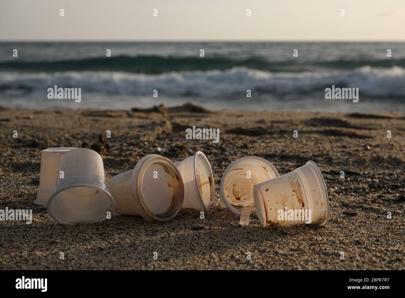 Les tasses à café sales jetables en plastique ont déchargé les déchets, jeté la pollution sur le rivage de mer Banque D'Images