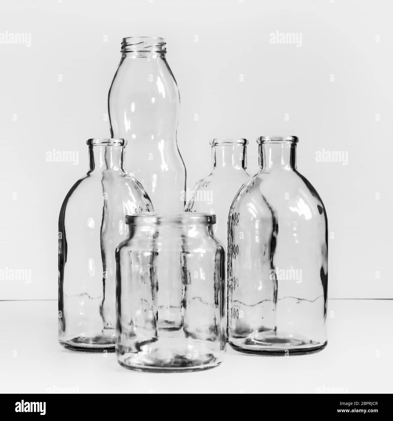 Plusieurs bouteilles et bocaux en verre transparent et vides. Arrière-plan noir et blanc vintage flou avec espace pour la copie. Mise au point sélective. Banque D'Images
