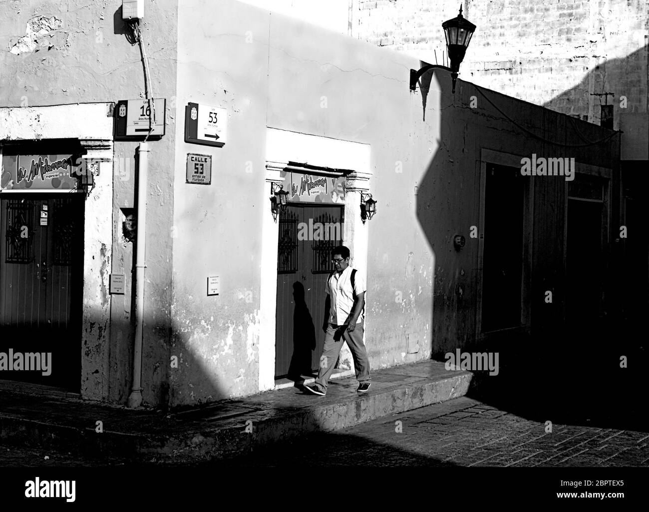 Photographie en noir et blanc d'un homme qui marche dans une rue dans le quartier historique de Campeche, au Mexique. Banque D'Images