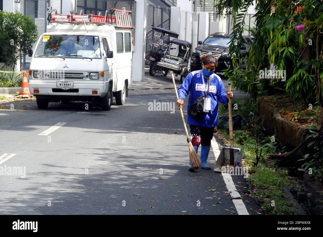 Antipolo City, Philippines - 16 mai 2020 : le balai de rue balaie la saleté et d'autres débris après une nuit de forte pluie et vent causés par le typhon Amb Banque D'Images