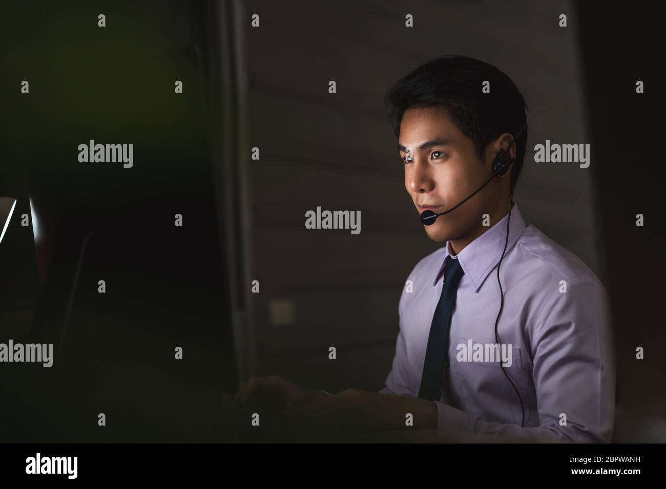 Service d'assistance à la clientèle asiatique homme souriant et travaillant dur tard dans la nuit, au bureau, au service du centre d'appels, aux employés et aux heures supplémentaires, 7 jours 24 heures su Banque D'Images