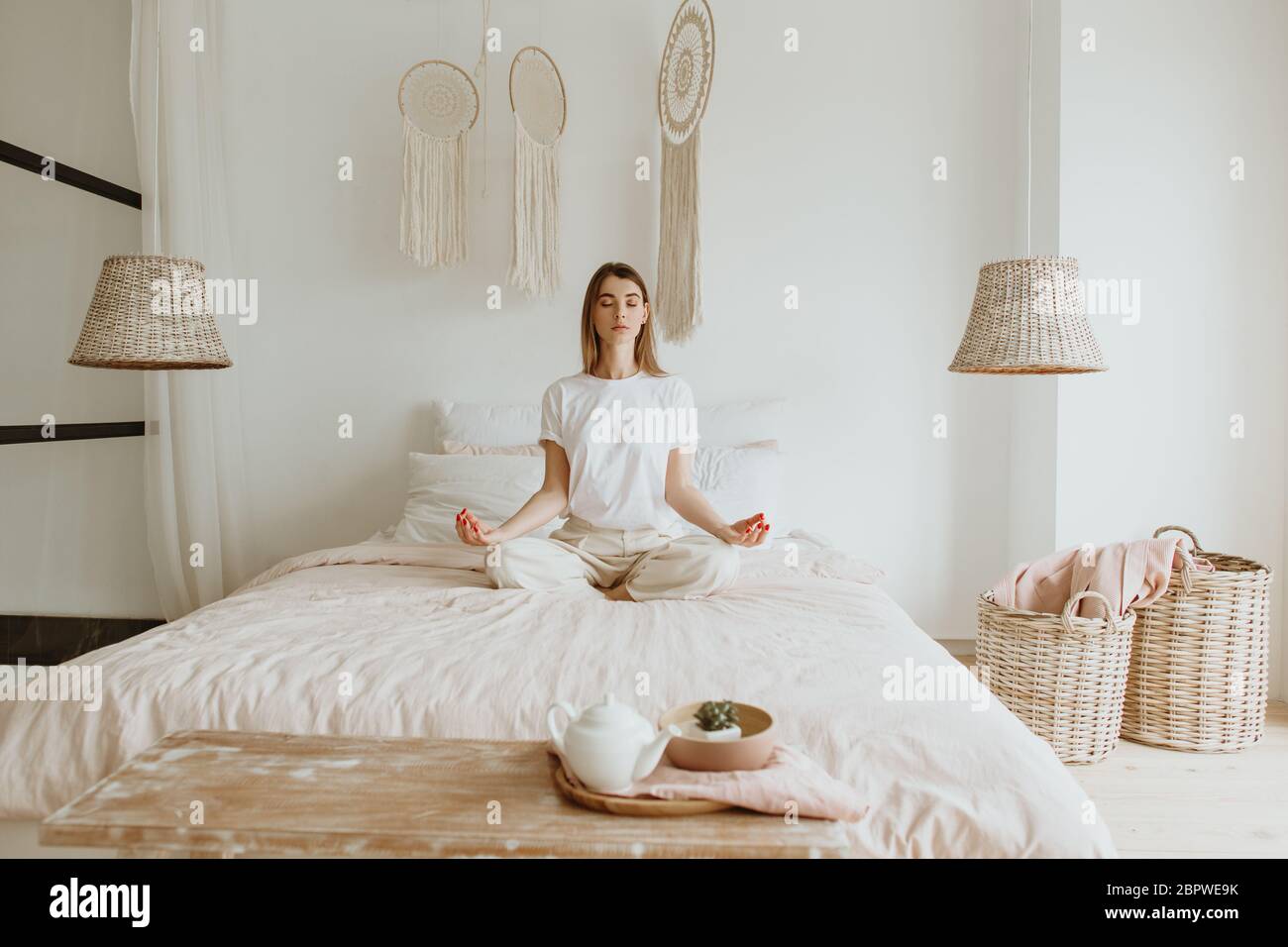 Belle jeune femme pratiquant la méditation sur le lit. Banque D'Images