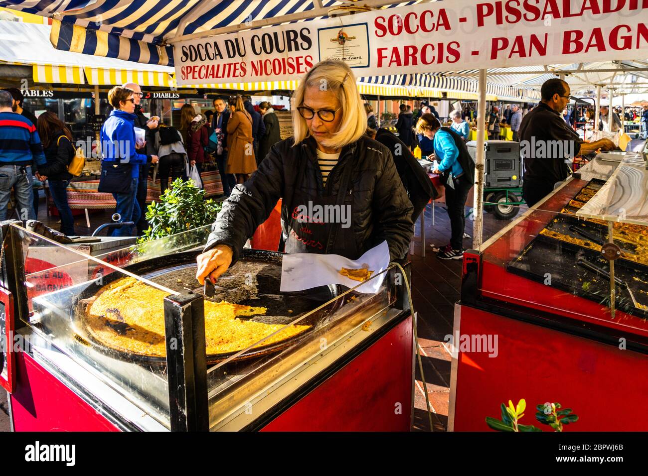 Nice, France, janvier 2020 – UNE femme qui coupe la « soca » sur le marché de cours Saleya. La SOCCA est une sorte de crêpe faite avec de la farine de pois chiches. Banque D'Images