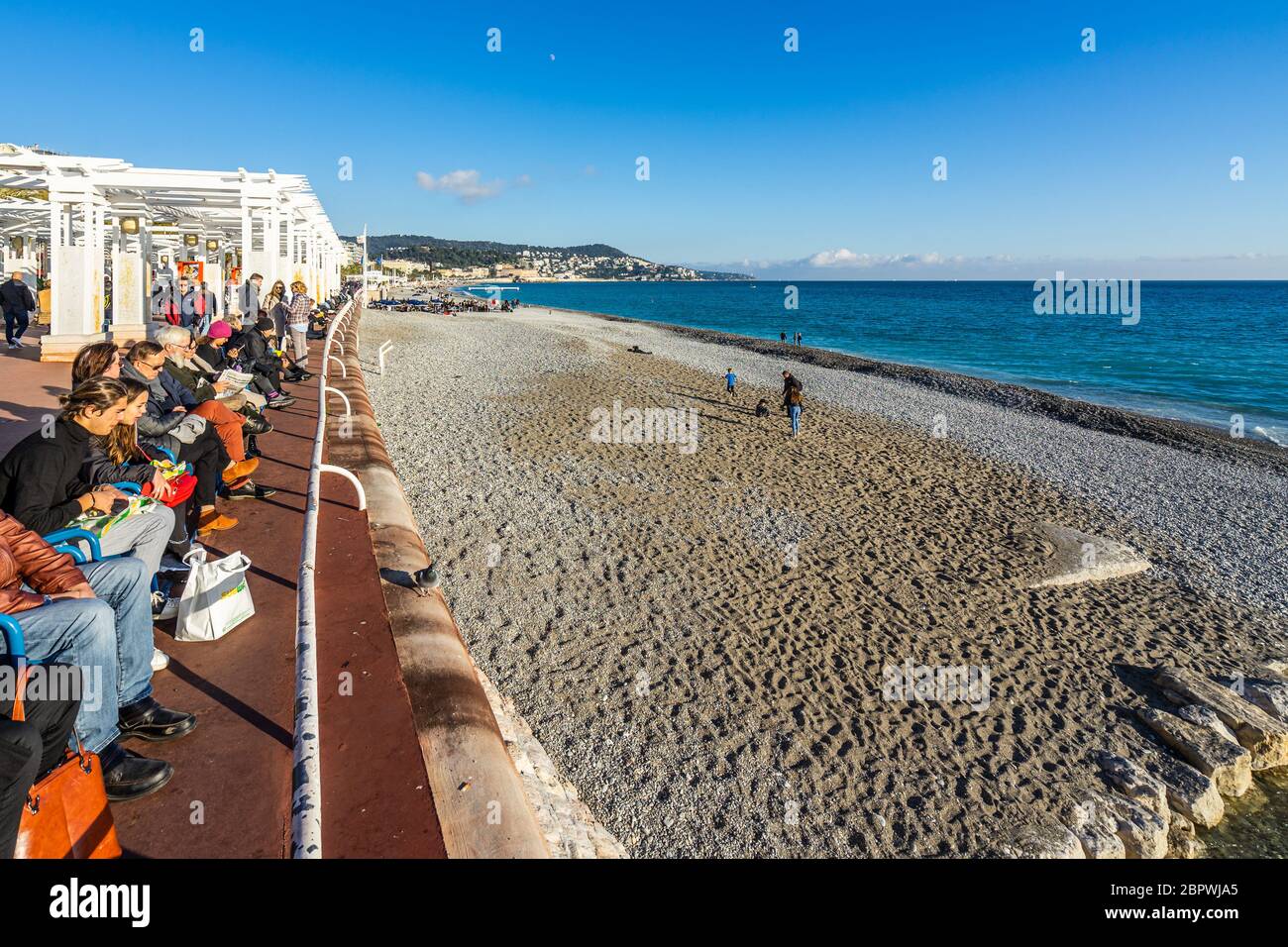 Nice, France, janvier 2020 - les gens se détendent par une journée ensoleillée sur la Promenade des Anglais, surplombant la plage de Neptune Banque D'Images