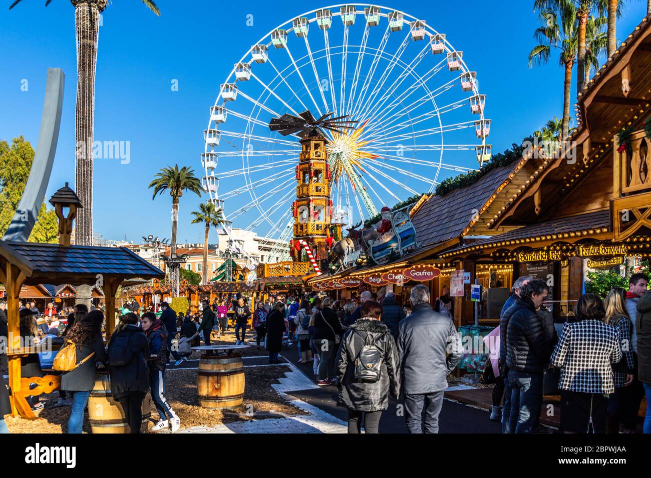 Les gens font du shopping entre les stands du marché de Noël de Nice sous la grande roue. Nice, France, janvier 2020 Banque D'Images