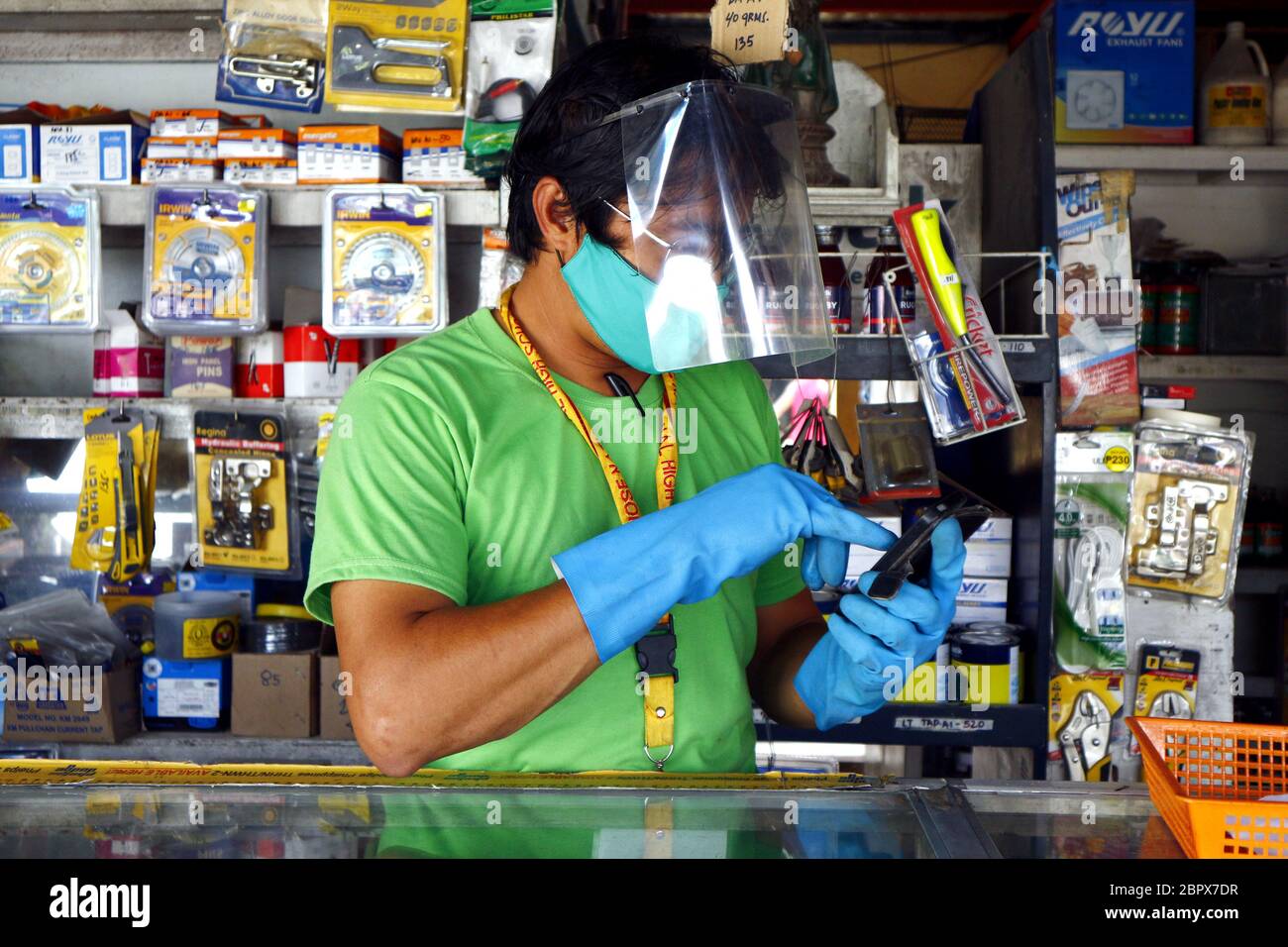 Antipolo City, Philippines - 16 mai 2020 : le propriétaire du magasin porte des gants, un masque et un masque facial comme mesure de précaution lorsque les entreprises ont été autorisées à ope Banque D'Images